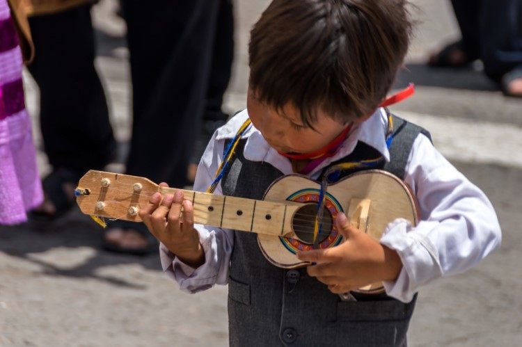 A child playing a small guitar in a carnaval parade in Ayacucho peru