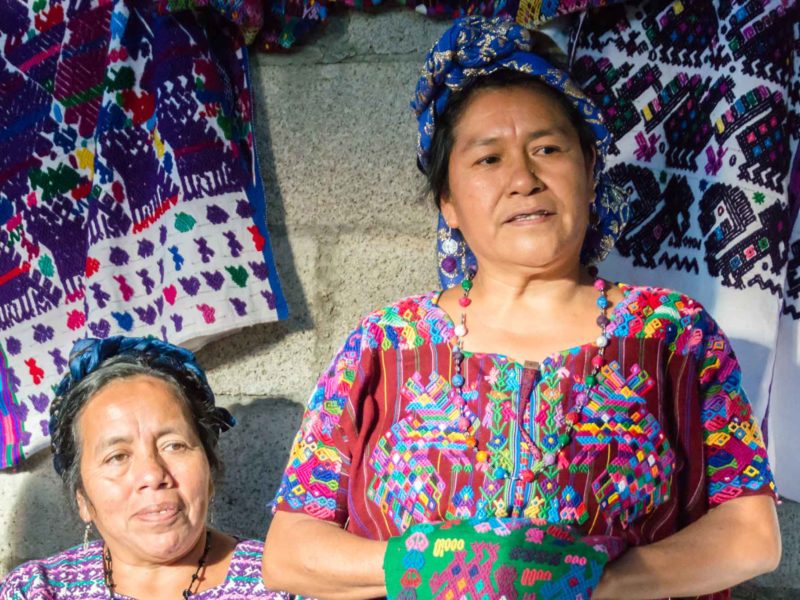 Two women from the Santo Domingo Xenacoj weaving community in Guatemala talk about their textiles to a group of responsible travelers