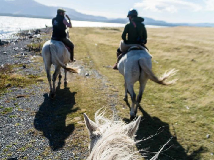 Two horses and riders on Seno Ultima Esperanza at Estancia La Peninsula in Chilean Patagonia