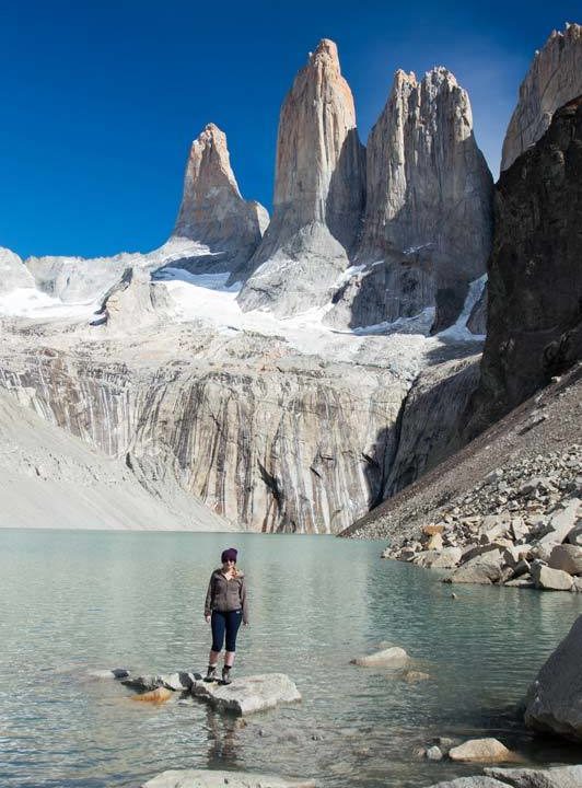 A hiker stands on a rock in front of Laguna Torres in Torres del Paine National Park along the W hike, a must-visit destination for any Patagonia itinerary