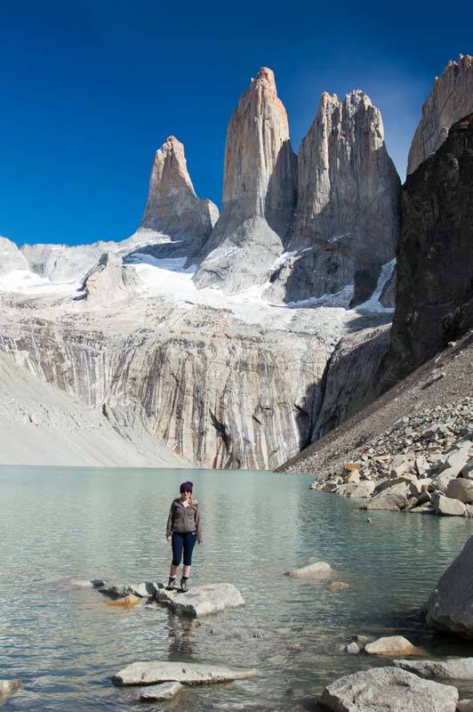 A hiker stands on a rock in front of Laguna Torres in Torres del Paine National Park along the W hike, a must-visit destination for any Patagonia itinerary