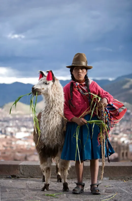 An indigenous woman dressed in traditional clothing in Cusco, Peru with a llama