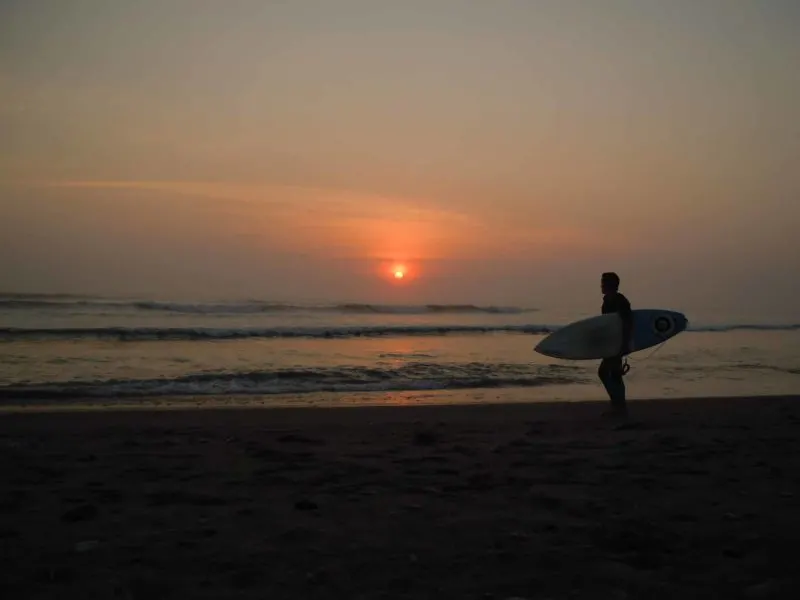 A surfer at sunset on Huanchaco beach near Trujillo in Peru
