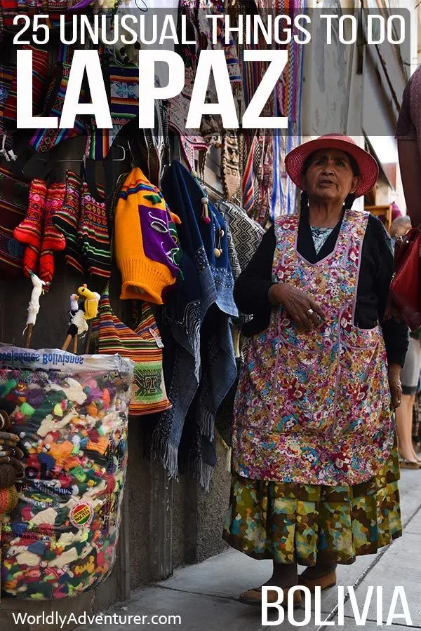 A stall within the clothes markets in La Paz with a local woman wearing a colourful hat and pinafore standing in front of her wares 