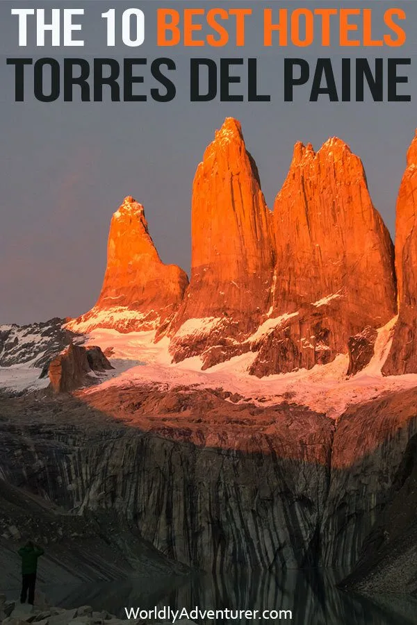 The torres in Torres del Paine National Park at dawn with a hiker standing at their base beside a lake