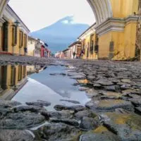 Cobblestones in Antigua Guatemala looking through a colonial archway to a volcano wreathed in morning mist