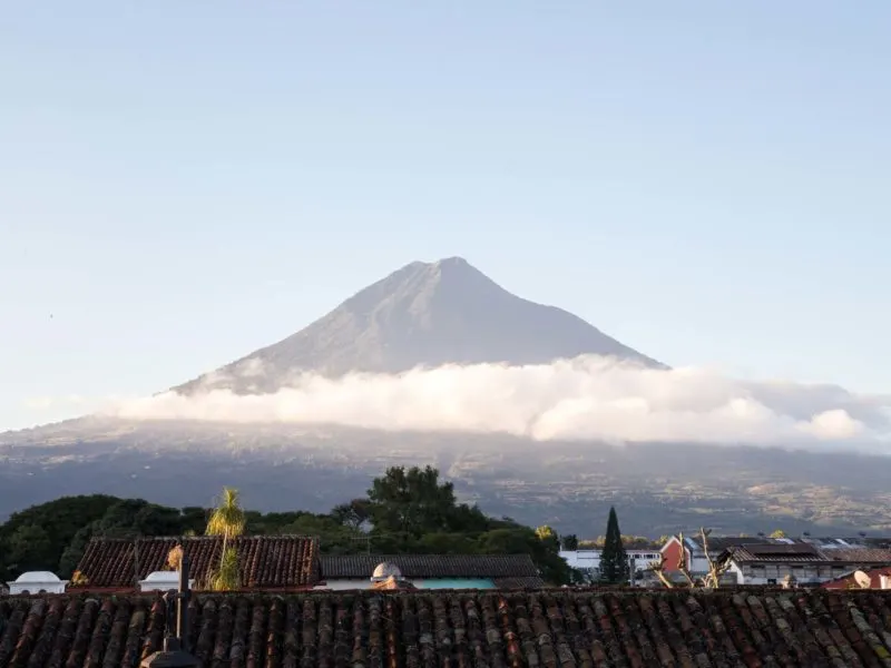 A volcano rises out of the clouds in Antigua Guatemala, a city you can visit can visit on a women travel group tour