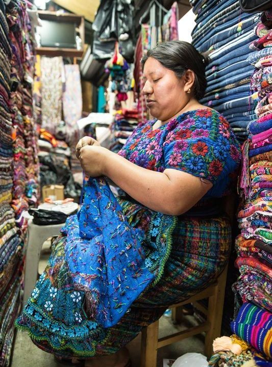 A woman sews at her textile stall in Antigua Guatemala, a city you can visit can visit on a women travel group tour