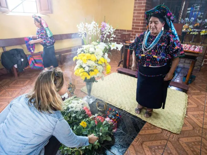 Presenting flowers in a shrine in the town of Santo Domingo Xenacoj in Guatemala, an experience you can have can visit on a women travel group tour