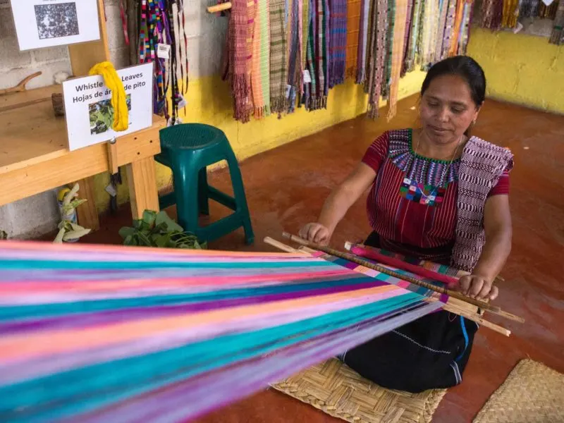 A woman weaves in the community of San Juan la Laguna where they dye textiles using organic dyes, a workshop you can take can visit on a women travel group tour