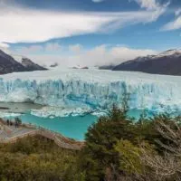 Views of the impressive snout of the Perito Moreno Glacier in Los Glaciares National Park with people stood on boardwalks beneath it.