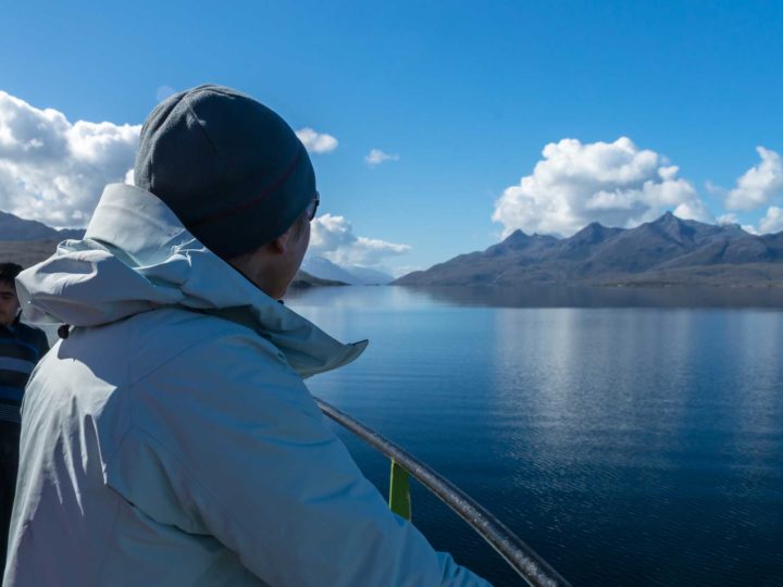 o persoană se uită în depărtare la peisajul fiordurilor Patagoniene la bordul unui feribot de marfă și pasageri,una dintre modalitățile de a ajunge în Patagonia