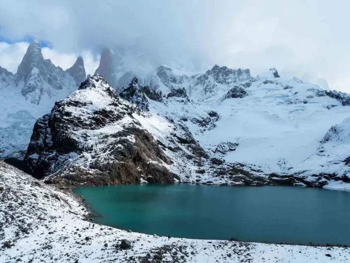 Snowy mountains surround a turquoise blue lake in the Parque Nacional Los Glaciares, Argentina. The best trek through this South American park.
