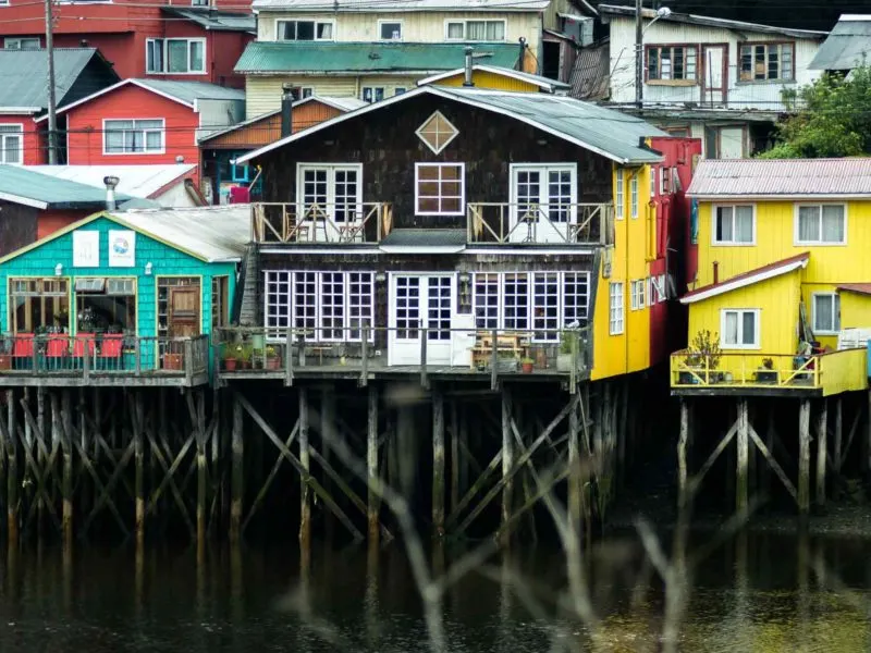 Cheerfully painted palafitos in the island of Chiloe on this South America Backpacking Route. 
