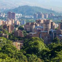 The city of Medellin with tower blocks rising out of the hillside and trees beneath