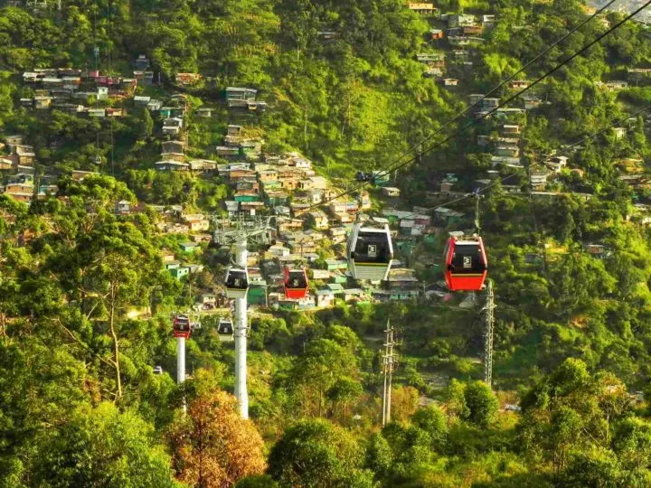 Red and green cable cars rising high above the city of Medellín, Colombia. 