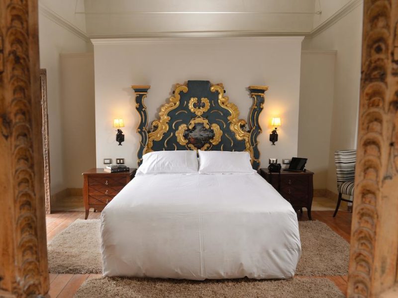 An elaborately carved and painted bed is the centerpiece of the otherwise simply decorated room in this boutique hotel