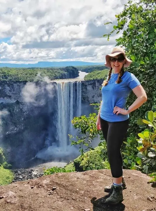 Steph Dyson of Worldly Adventurer posing in front of Kaieteur Falls, one of the world's highest waterfalls located in Guyana, South America