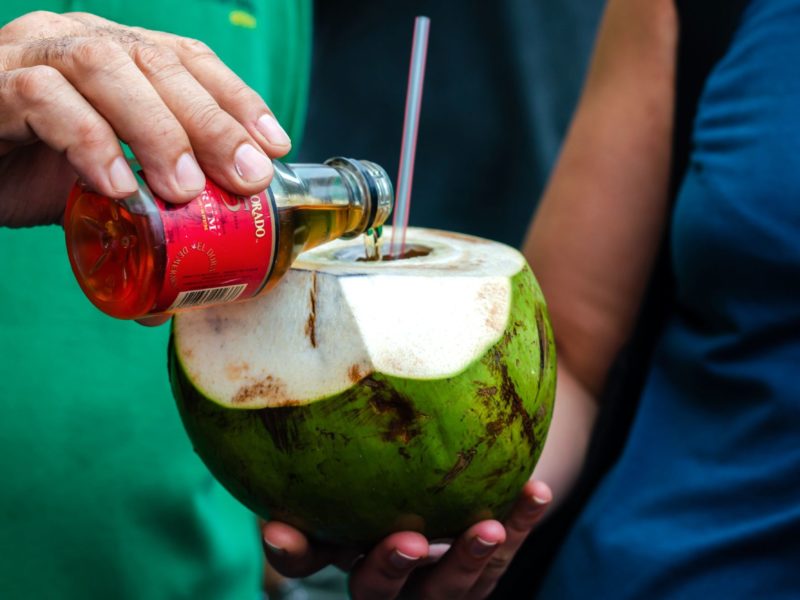 In Guyana a man adds rum to a coconut to create a popular local drink.