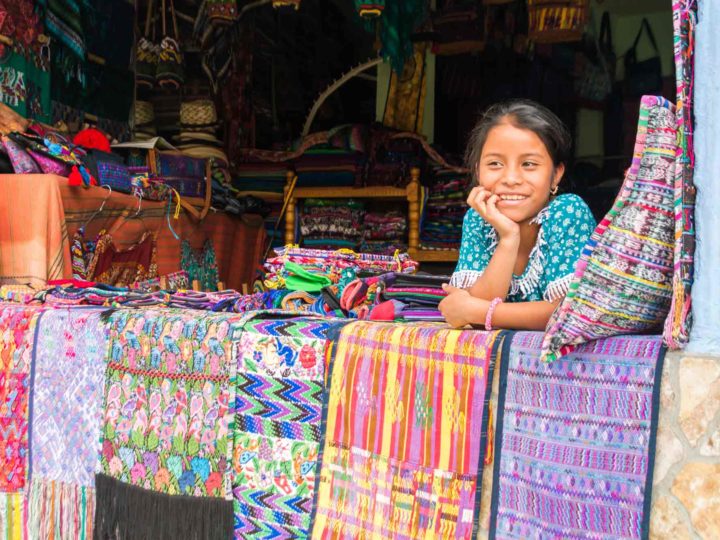 A girl leans over textiles at a stall in Panajachel, a village on the shores of Lago de Atitlan, a must-visit destination on any Guatemala itinerary