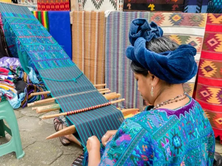 A woman weaves at a loom in Panajachel, an unmissable destination on a guatemala itinerary