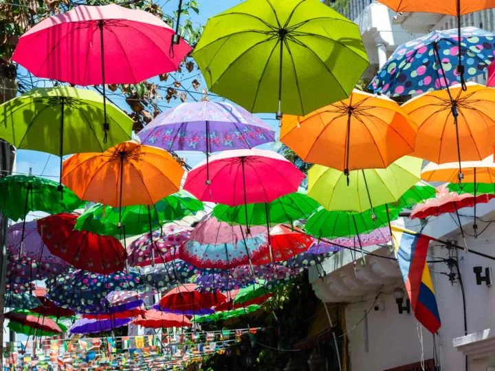 Colourful umbrellas hanging above the street in the quirky Getsemani neighbourhood - a great place to stay in Cartagena.