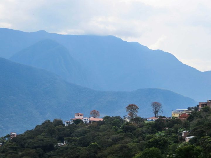 Buildings in the village of Coroico on a vegetated ridge with high mountains behind