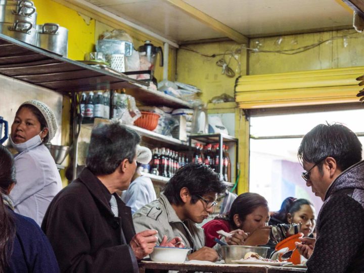 Local pacenos eat lunch at a market stall in La Paz, Bolivia