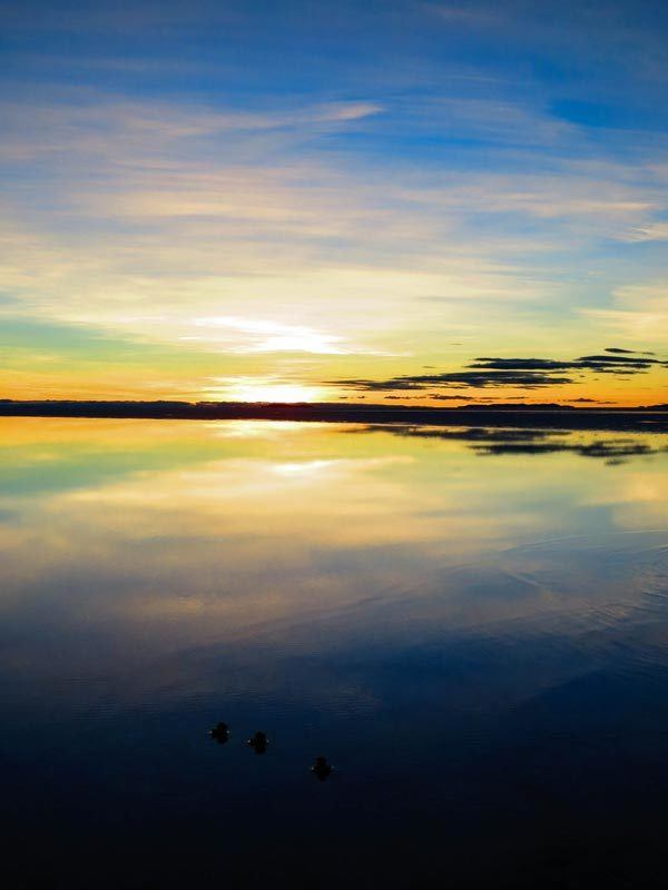 The Salar de Uyuni in Bolivia with water on top reflecting the sunrise like a mirror