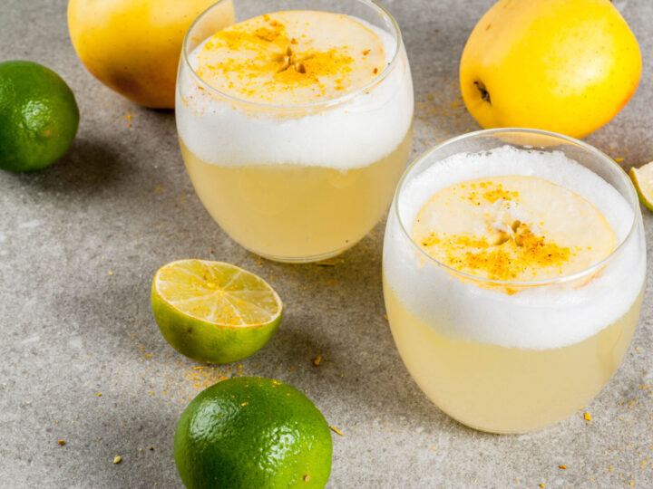 Two pisco sours, made from pisco, lemon juice, simple syrup, bitters and topped with egg white.