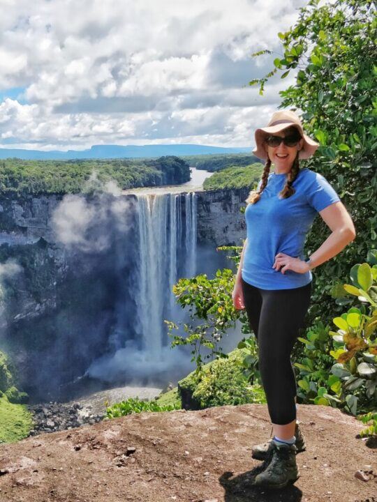 Steph Dysn, founder of Worldly Adventurer and a travel journalist, poses in front of Kaieteur Falls in Guyana