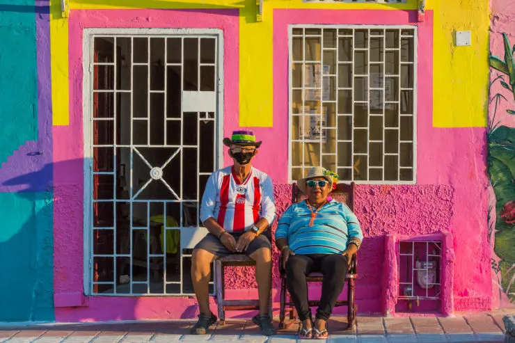 Two men sit outside a colourful building in the town of Baranquilla, a day trip away from Cartagena in Colombia