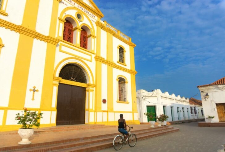 A woman riding a bicycle in front of the cathedral in Mompox, Colombia 