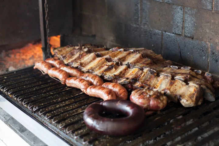 Steak and chorizo sausage on an open grill in Argentina (and one of the reason it's one of the best countries to visit in South America)