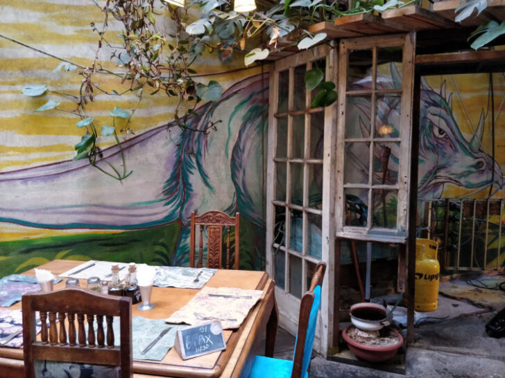 Outside patio with a table, decorated with a painted mural on the wall