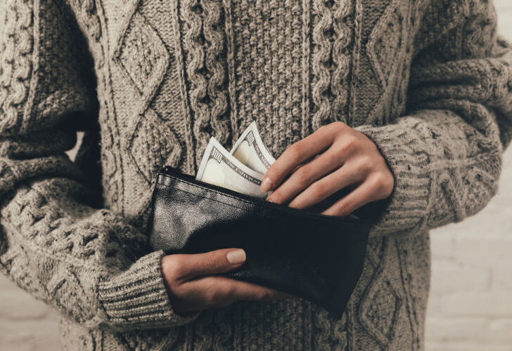 A person with a wallet filled with dollars