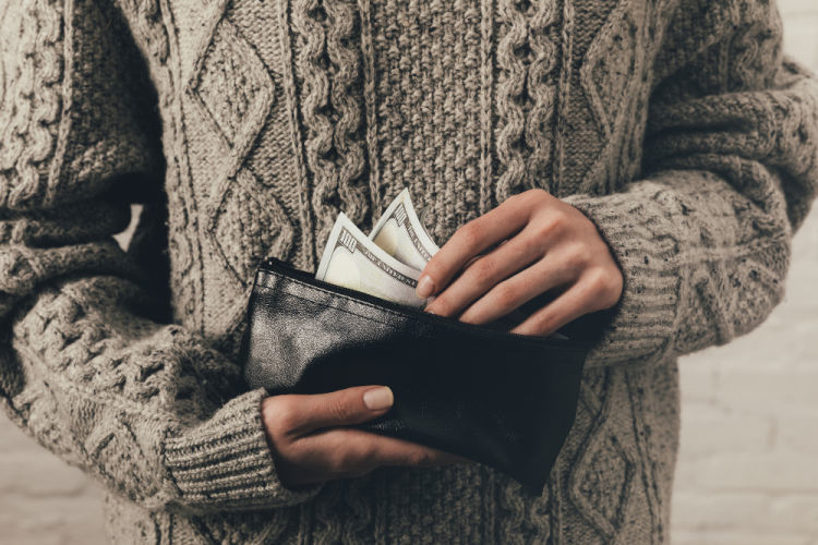 A woman in a jumper holder dollar bills and a wallet