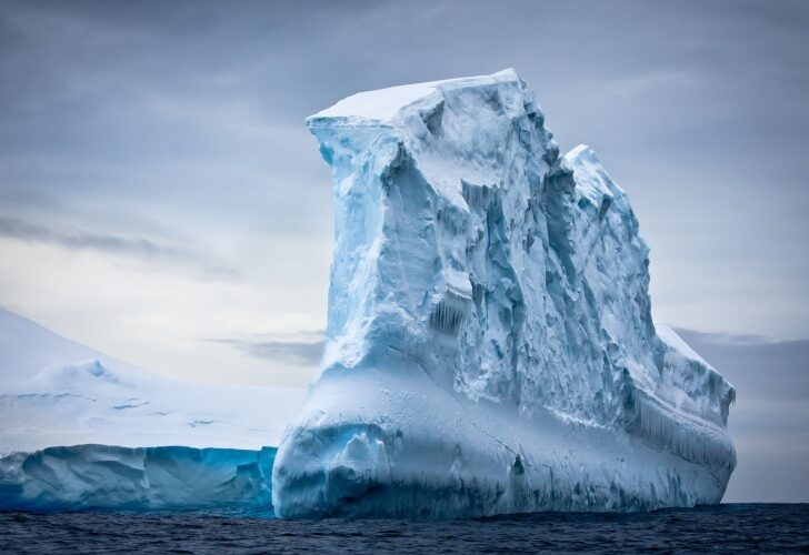 A snowy Antarctic iceberg, set in the ocean.
