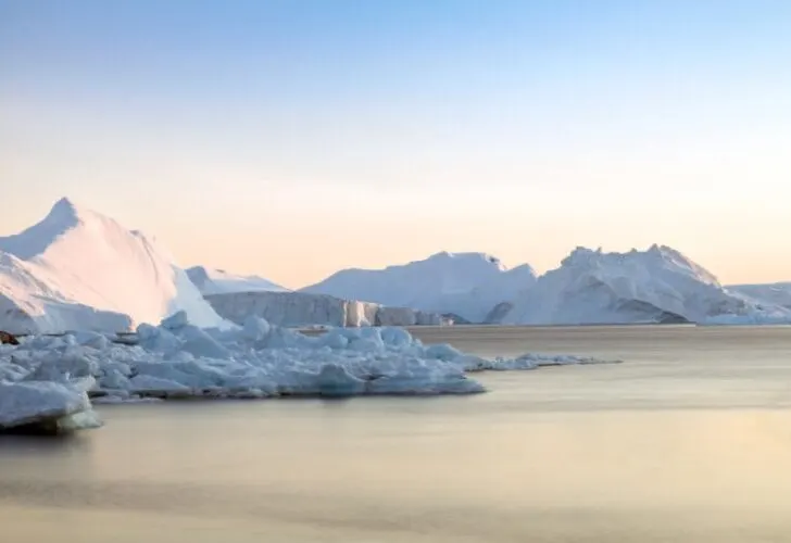 Antarctic iceberg in the snow as sun rises.