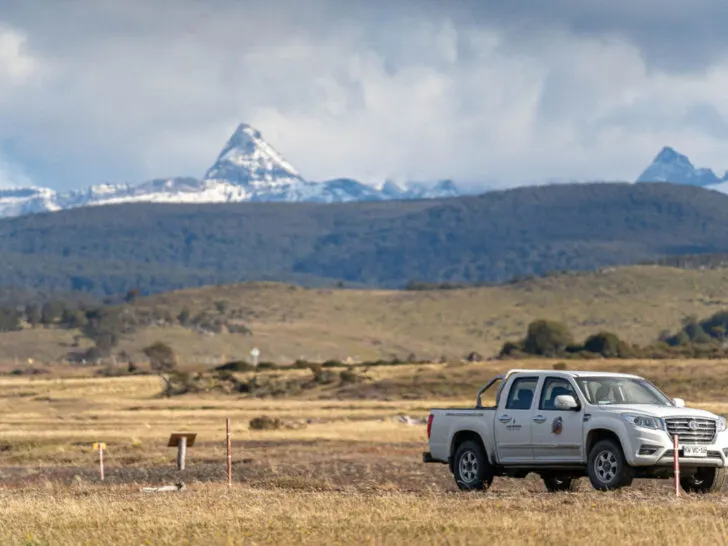 A truck parked on grasslands with mountains behind in Chilean Patagonia on the island of Tierra del Fuego