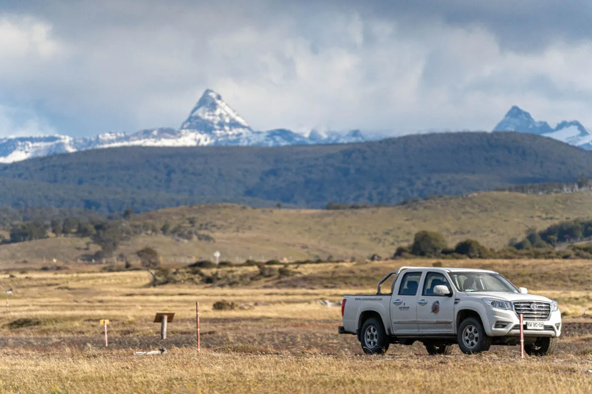 A truck parked on grasslands with mountains behind in Chilean Patagonia on the island of Tierra del Fuego