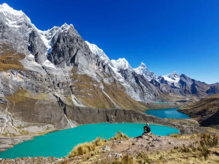 A hiker looks out to the Cordillera Huayhuash mountain and lake views in Peru.
