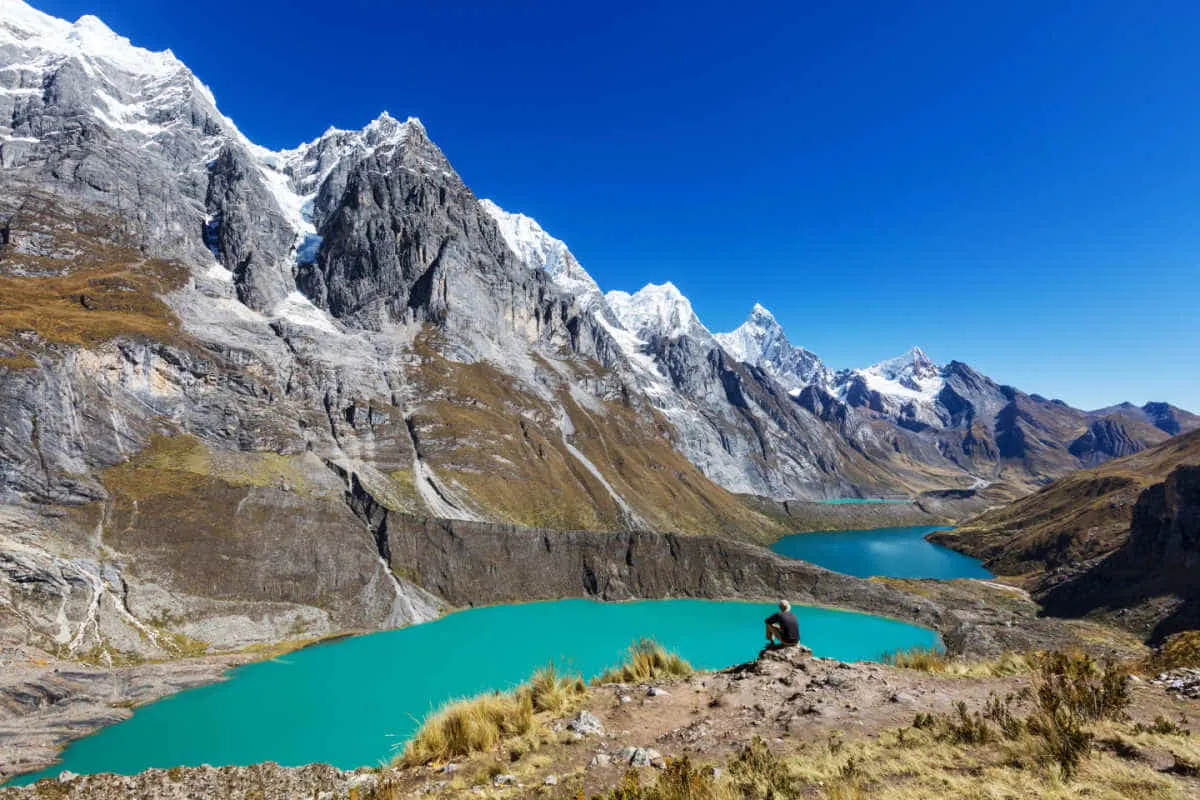 A hiker looks out to the Cordillera Huayhuash mountain and lake views in Peru.